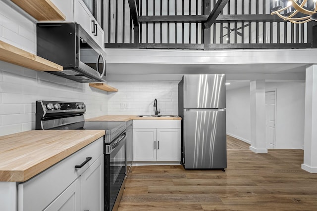 kitchen featuring appliances with stainless steel finishes, dark hardwood / wood-style floors, white cabinetry, sink, and butcher block counters