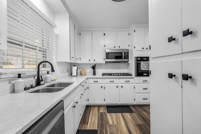 kitchen with sink, dark wood-type flooring, appliances with stainless steel finishes, white cabinetry, and decorative backsplash