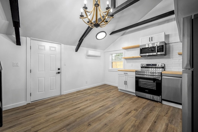 kitchen featuring pendant lighting, butcher block counters, vaulted ceiling with beams, white cabinets, and stainless steel appliances