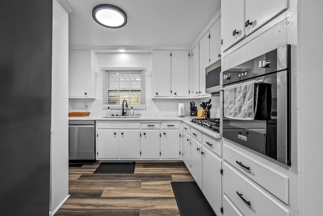 kitchen with sink, white cabinetry, appliances with stainless steel finishes, dark hardwood / wood-style flooring, and backsplash