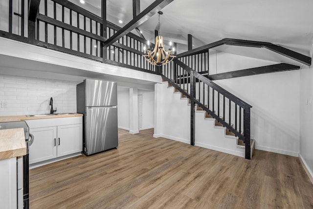 stairs featuring hardwood / wood-style flooring, high vaulted ceiling, sink, and a chandelier