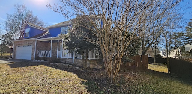 view of front of house with a porch, brick siding, fence, concrete driveway, and a front lawn