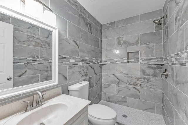 bathroom with tile walls, tasteful backsplash, toilet, a shower stall, and vanity