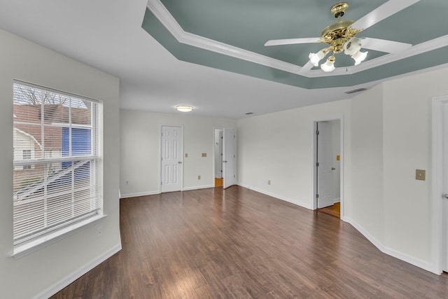 spare room with a tray ceiling, dark wood finished floors, visible vents, a ceiling fan, and baseboards