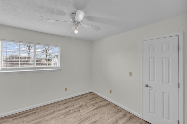 empty room with light wood finished floors, a ceiling fan, baseboards, and a textured ceiling