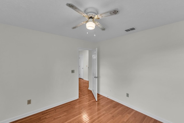 unfurnished room featuring a ceiling fan, visible vents, light wood-style flooring, and baseboards