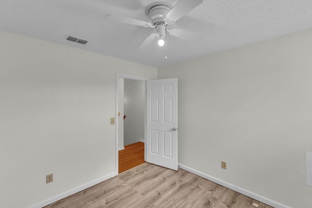 spare room with visible vents, light wood-style floors, ceiling fan, a textured ceiling, and baseboards