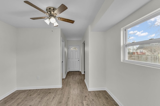 empty room featuring light wood-style flooring, baseboards, and a ceiling fan