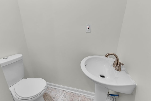 bathroom featuring a sink, toilet, and baseboards