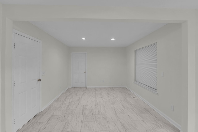 spare room featuring recessed lighting and baseboards