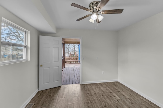 interior space featuring a ceiling fan, visible vents, baseboards, and wood finished floors