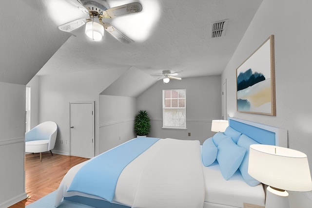 bedroom featuring lofted ceiling, visible vents, a ceiling fan, a textured ceiling, and wood finished floors