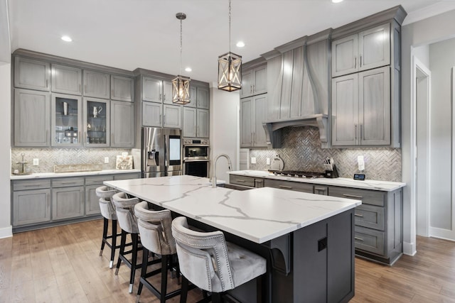 kitchen with sink, a breakfast bar area, hanging light fixtures, a large island with sink, and stainless steel appliances