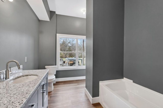 bathroom featuring vanity, a washtub, hardwood / wood-style flooring, and toilet