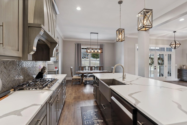 kitchen featuring sink, stainless steel gas cooktop, light stone counters, hanging light fixtures, and dishwashing machine