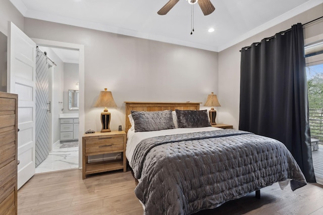 bedroom featuring crown molding, a barn door, and light hardwood / wood-style floors