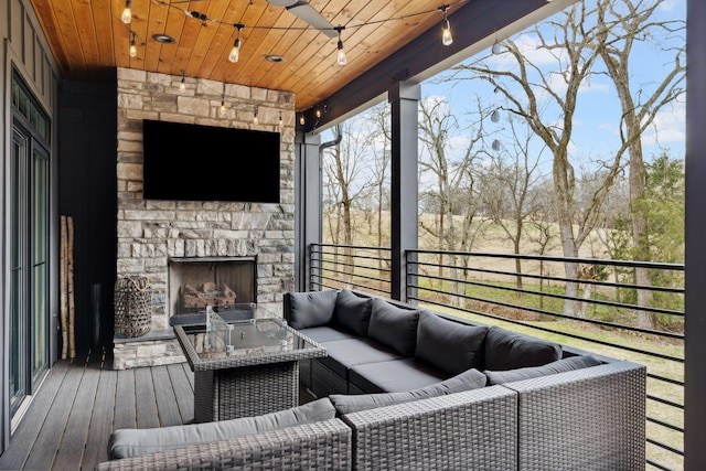 sunroom / solarium with an outdoor stone fireplace and wood ceiling