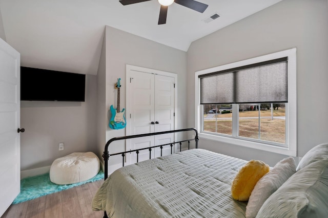 bedroom with ceiling fan, wood-type flooring, a closet, and lofted ceiling