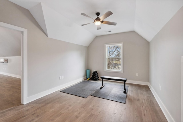 workout room with vaulted ceiling, light hardwood / wood-style floors, and ceiling fan