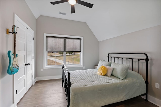 bedroom with ceiling fan, light hardwood / wood-style floors, and vaulted ceiling