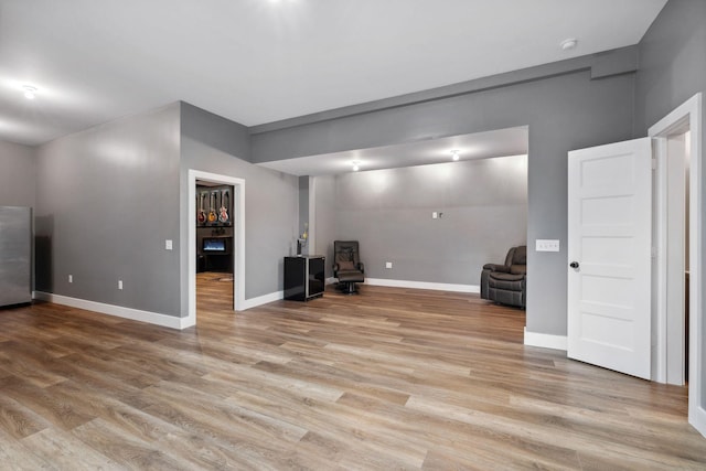 basement featuring stainless steel fridge and light wood-type flooring