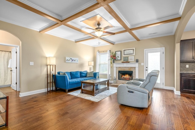 living room with hardwood / wood-style floors, a fireplace, beamed ceiling, coffered ceiling, and ceiling fan