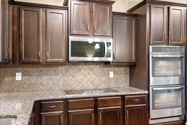 kitchen featuring decorative backsplash, appliances with stainless steel finishes, light stone countertops, and dark brown cabinets