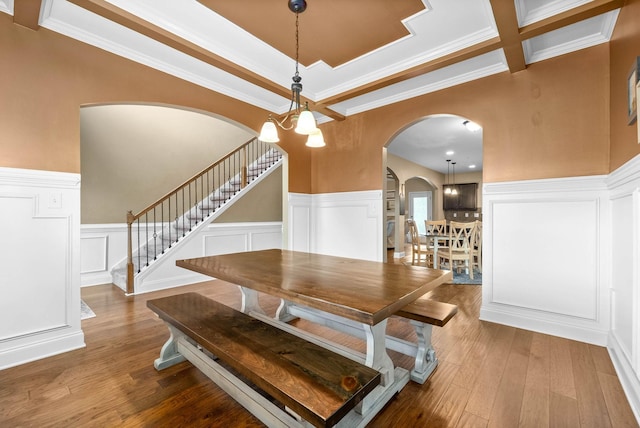 dining area featuring beamed ceiling, ornamental molding, wood-type flooring, and a chandelier