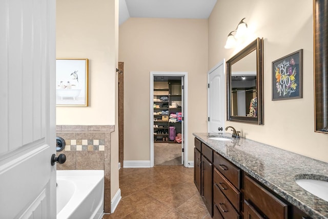 bathroom with lofted ceiling, vanity, a bathing tub, and tile patterned flooring