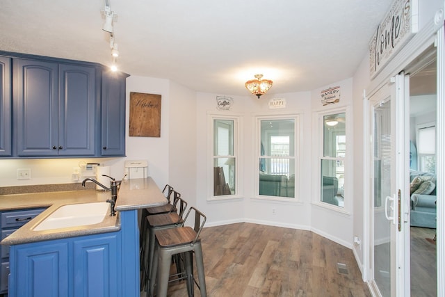 kitchen featuring blue cabinets, a kitchen breakfast bar, dark hardwood / wood-style flooring, and sink