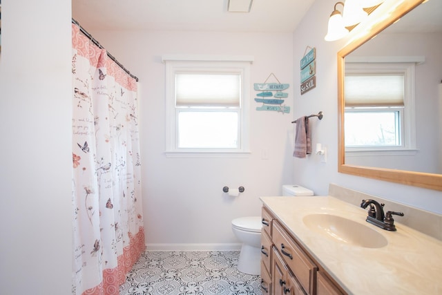 bathroom with a healthy amount of sunlight, toilet, tile patterned flooring, and vanity