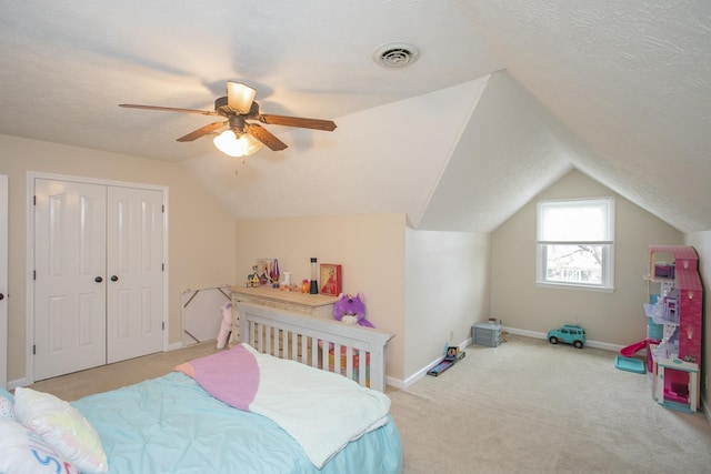 bedroom featuring lofted ceiling, ceiling fan, a textured ceiling, light carpet, and a closet