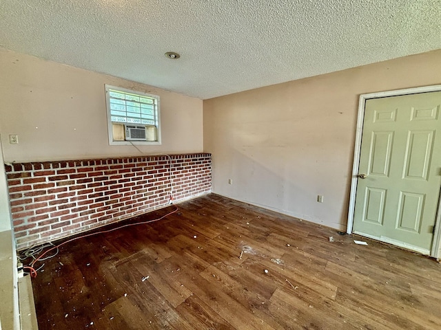 empty room with cooling unit, dark wood-type flooring, and a textured ceiling