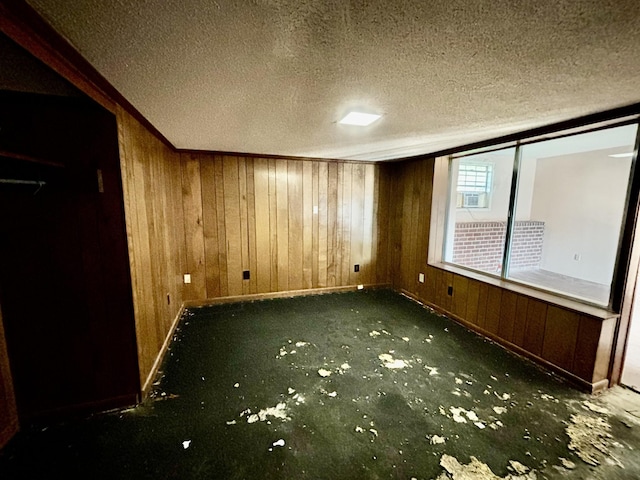 unfurnished room featuring a textured ceiling and wood walls