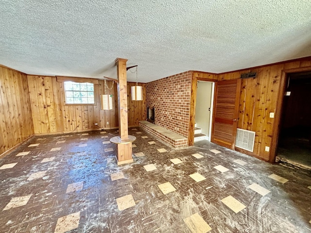 unfurnished living room featuring a textured ceiling and wood walls