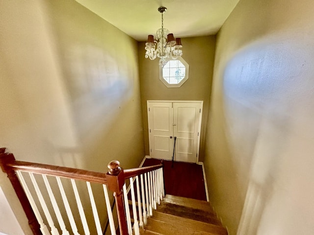 stairs with wood-type flooring and a notable chandelier