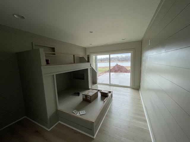 bedroom with light hardwood / wood-style flooring, access to outside, and wooden walls