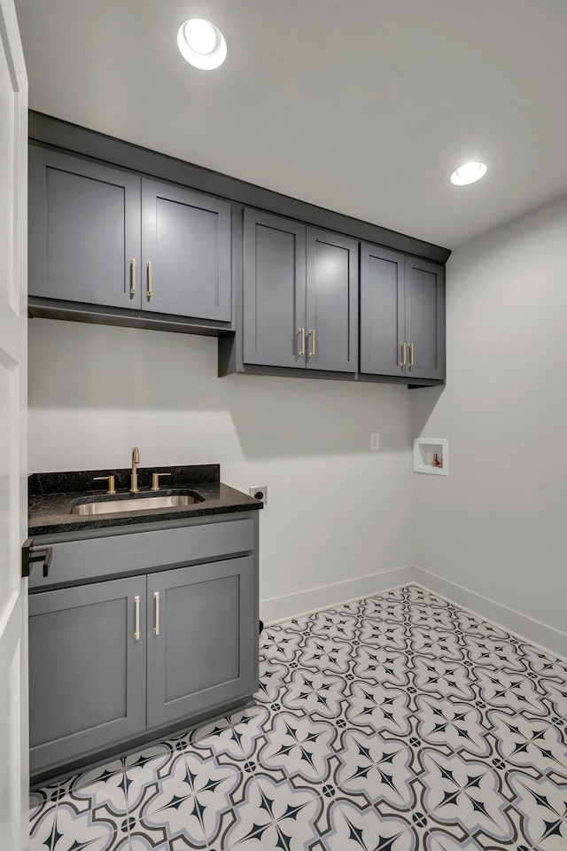 clothes washing area with cabinet space, hookup for a washing machine, baseboards, and a sink