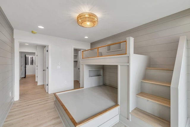 bedroom with baseboards, wood walls, light wood-style flooring, and recessed lighting