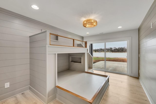 unfurnished bedroom featuring a water view, light wood finished floors, access to outside, and recessed lighting