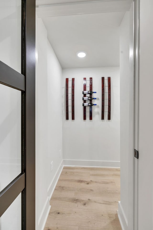 corridor with baseboards and light wood finished floors