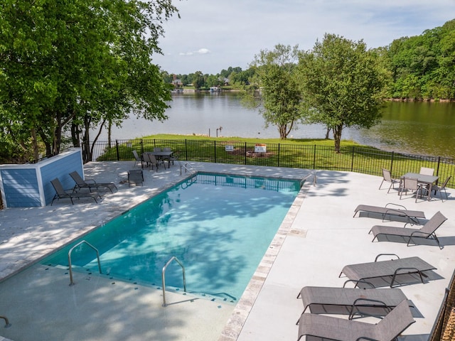 pool with a water view, a patio area, and fence