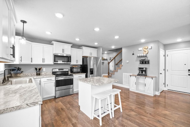 kitchen with pendant lighting, stainless steel appliances, sink, and white cabinets