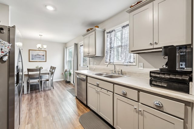 kitchen with sink, appliances with stainless steel finishes, gray cabinetry, hanging light fixtures, and light wood-type flooring