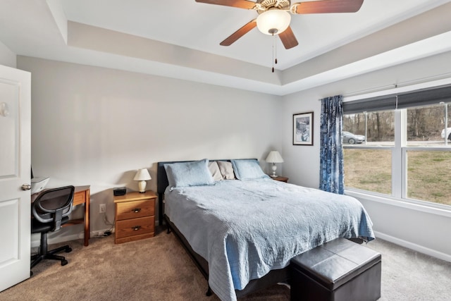 carpeted bedroom with ceiling fan and a tray ceiling