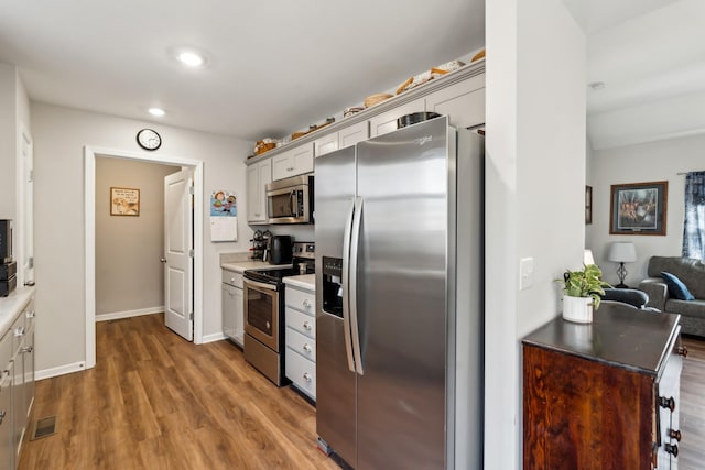 kitchen with gray cabinets, appliances with stainless steel finishes, and dark hardwood / wood-style flooring