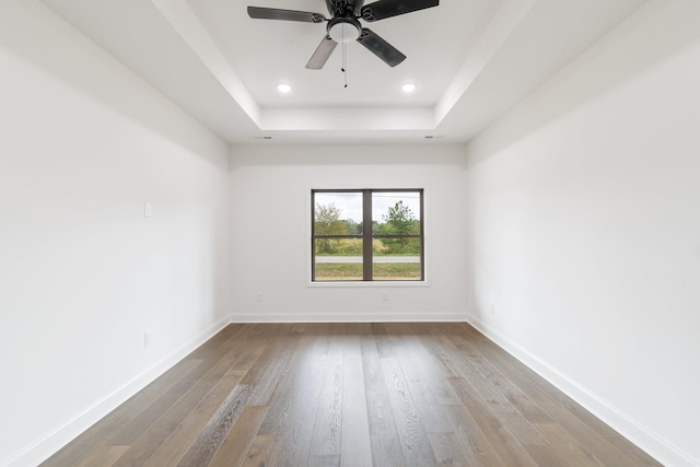 spare room with hardwood / wood-style floors, a raised ceiling, and ceiling fan