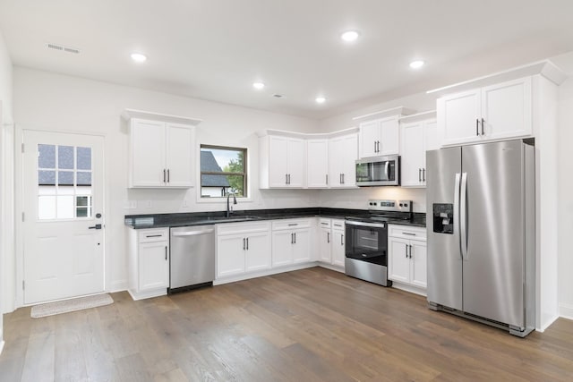 kitchen with appliances with stainless steel finishes, dark hardwood / wood-style flooring, sink, and white cabinets