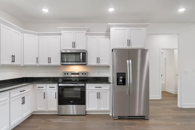 kitchen with white cabinetry, dark hardwood / wood-style floors, dark stone counters, and appliances with stainless steel finishes