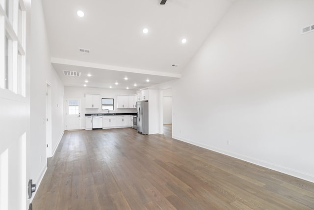 unfurnished living room with sink, wood-type flooring, and high vaulted ceiling